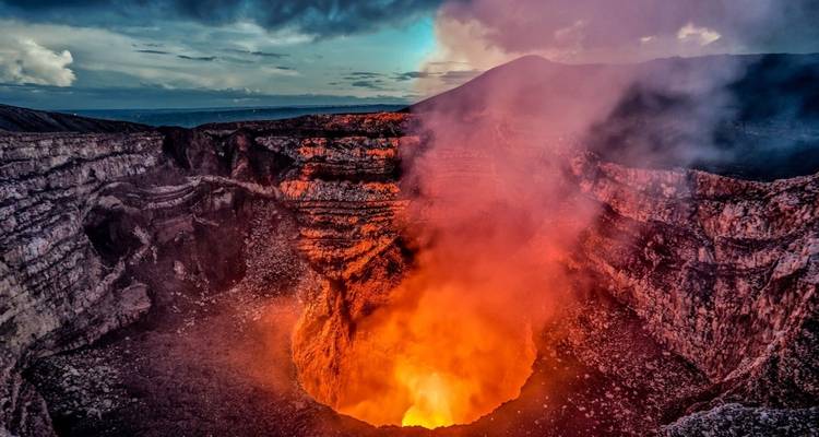 Lava glowing in the crater of an active volcano at dusk.