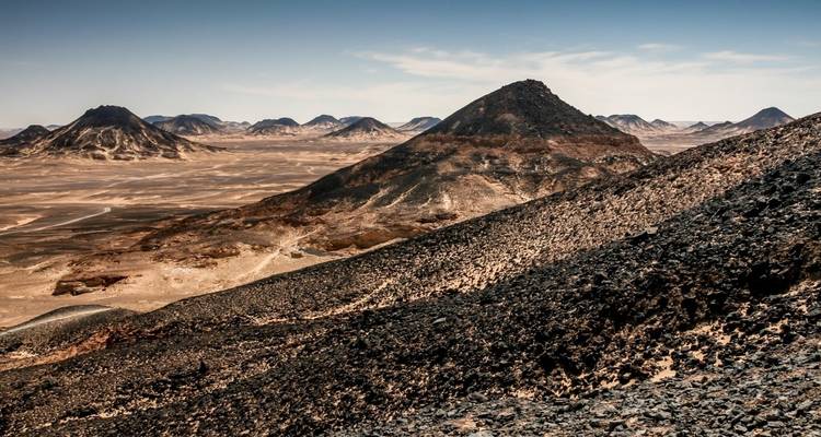 Schwarze Wüstenhügel unter einem klaren blauen Himmel.