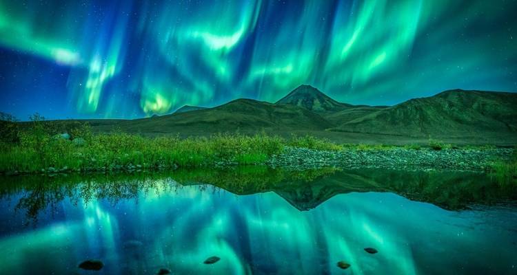 Aurores boréales au-dessus d'un paysage de montagne.