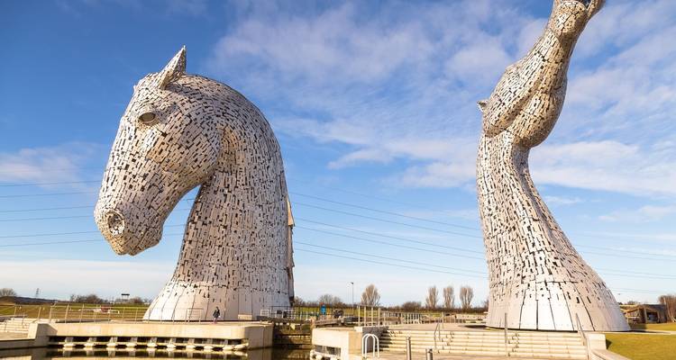 Les imposantes sculptures en acier en forme de têtes de chevaux connues sous le nom de Kelpies se dressent sous un ciel bleu.