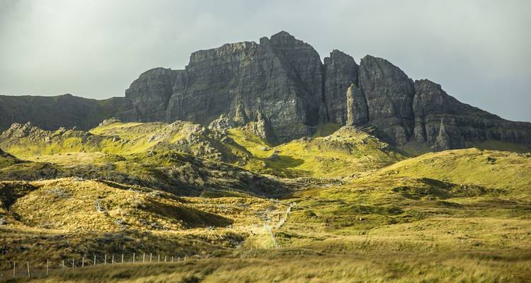 La lumière du soleil baigne les formations de pinacles spectaculaires du Old Man of Storr sur les pentes herbeuses.