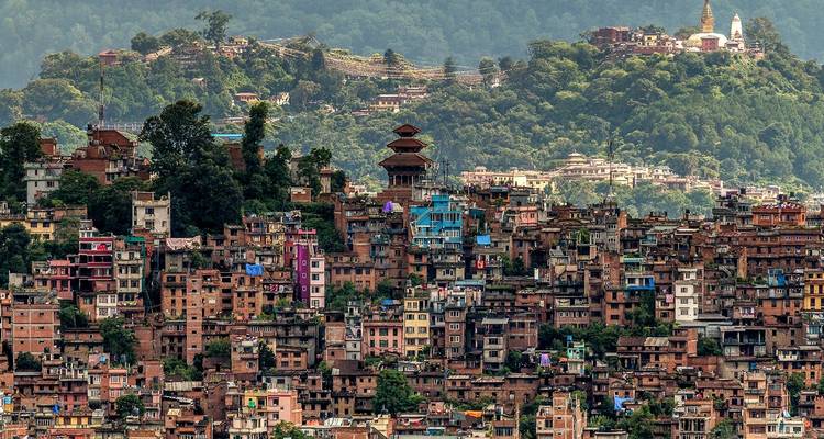 Luftaufnahme eines dicht bebauten Gebiets mit Hügeln im Hintergrund.