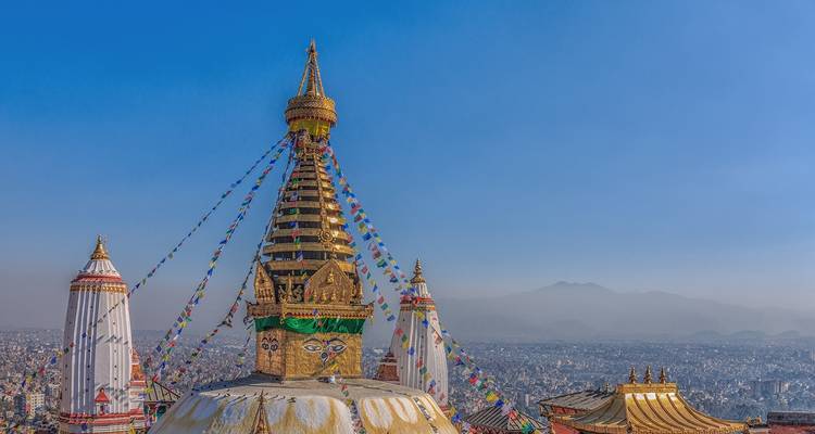 Eine Stupa mit Gebetsfahnen und einem Panoramablick auf die Stadt.