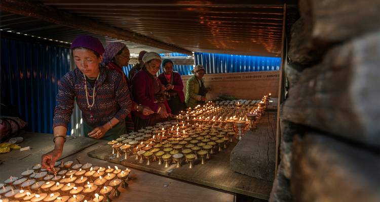 Frauen zünden Kerzen in einem überdachten Bereich an.