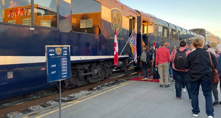 Passengers boarding a train at a platform with a flag visible.