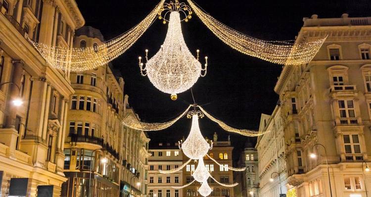 Luces navideñas estilo candelabro brillantes cuelgan sobre una elegante calle europea por la noche.