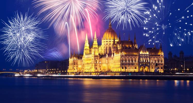Le Parlement de Budapest brillant dans la nuit sous des feux d'artifice éclatants au-dessus du Danube.
