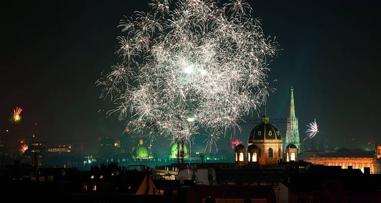 Les feux d'artifice nocturnes éclatant au-dessus de la ligne d'horizon de Vienne, mettant en évidence les dômes et les flèches d'églises.
