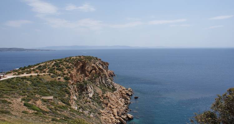 Klippe mit Blick auf ein blaues Meer mit entfernten Inseln.