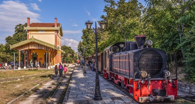 Vintage treinstation met een oude stoomlocomotief en wachtende mensen.