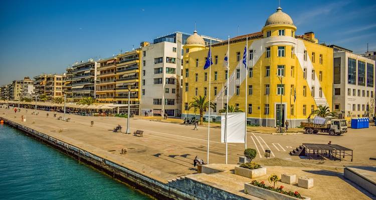Modern gebouw langs een boulevard aan zee in een zonnige kuststad.