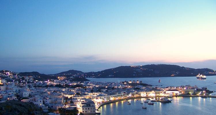 Panoramic view of Mykonos town and harbor at sunset.