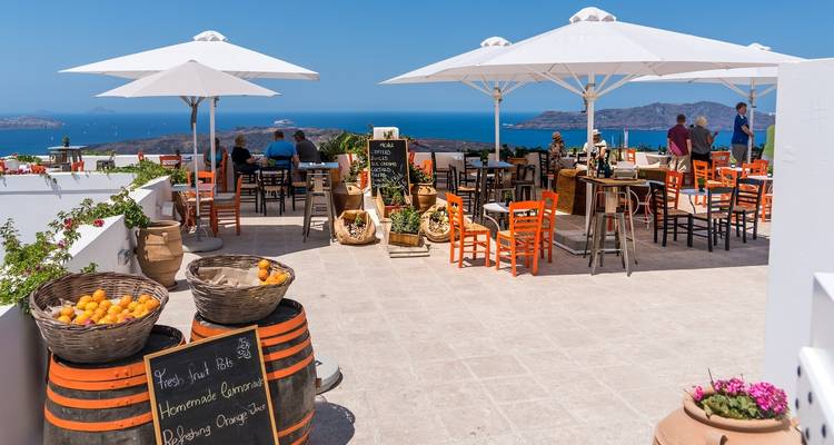 Buitenrestaurant met mensen en uitzicht op zee.
