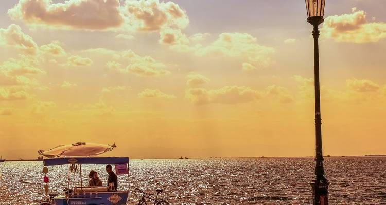 Boat with people on a shimmering sea at sunset.