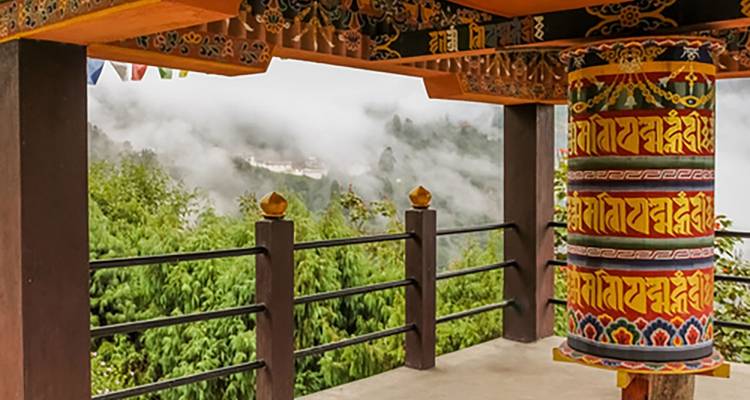 Buntes Gebetsrad in einer nebligen Hügellandschaft.