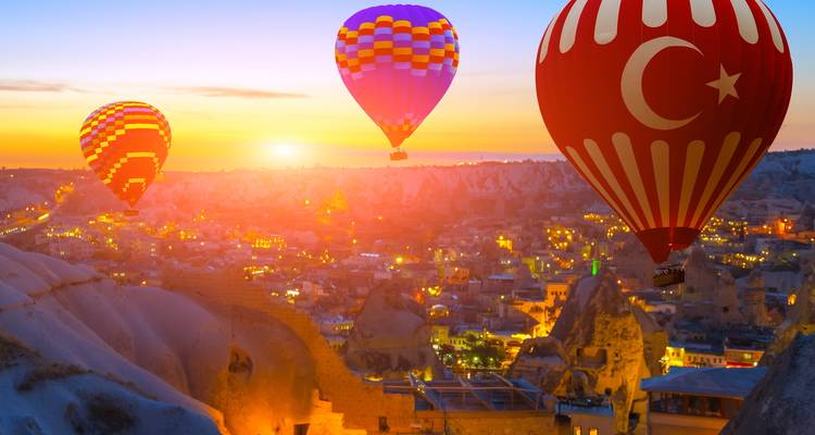 Heißluftballons, die bei Sonnenuntergang aufsteigen, mit einer türkischen Flagge an einem Ballon.
