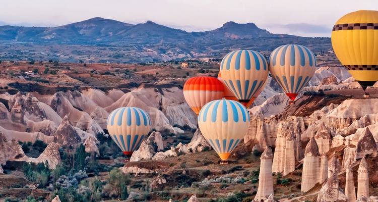 Mehrere Heißluftballons schweben über einzigartigen Felsformationen.