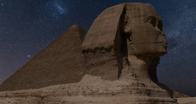 Le Sphinx sous un ciel étoilé nocturne avec la Grande Pyramide en arrière-plan.