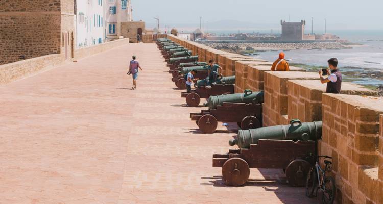 Remparts historiques en bord de mer bordés de vieux canons surplombant l'Atlantique, avec quelques visiteurs qui se promènent.