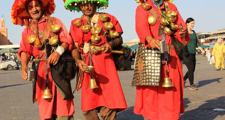 Kleurrijke straatartiesten in traditionele Marokkaanse klederdracht die waterkannen dragen.