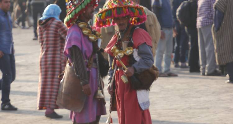 Blurred image of men in traditional attire with brass cups.