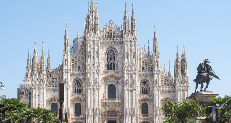 La intrincada fachada de mármol del Duomo de Milán con palmeras en primer plano