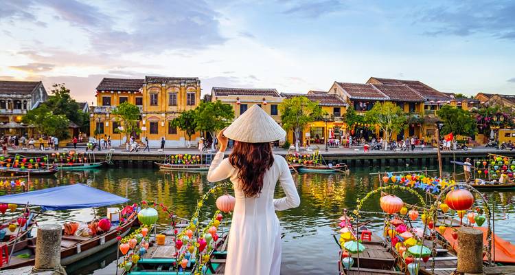 Woman in traditional dress overlooking a vibrant riverside town.