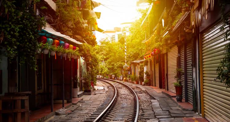 Narrow street with railway tracks amid colorful shops.