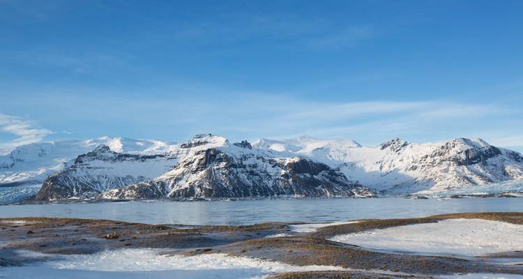 Montagnes côtières enneigées aux rivages glacés.