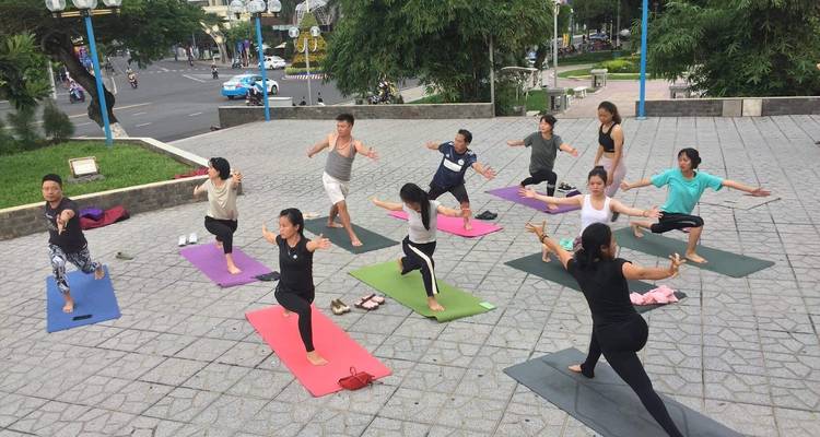 Outdoor yoga class on patterned mats overlooking a city.