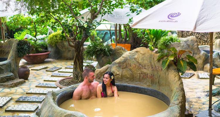 A couple enjoying a mud bath in a tropical garden.