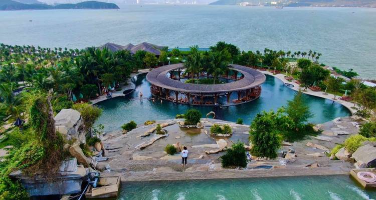 Aerial view of a tropical resort with a large pool and ocean backdrop.