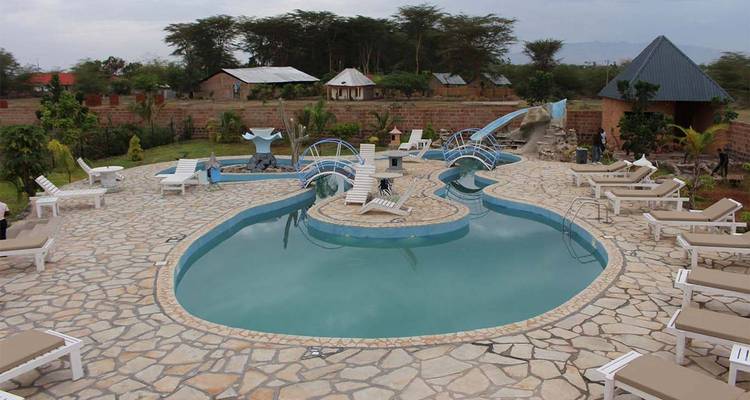 Schwimmbadbereich in einem Resort mit Liegestühlen und einer Wasserrutsche.