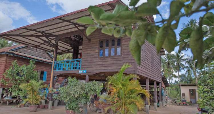 Casa tradicional khmer elevada de madera rodeada de plantas tropicales