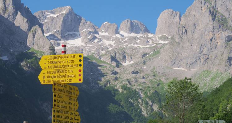 Sommets de montagne avec un panneau directionnel au premier plan.