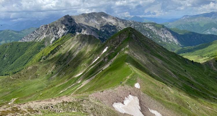Chaîne de montagnes avec des crêtes couvertes d'herbe et des plaques de neige.