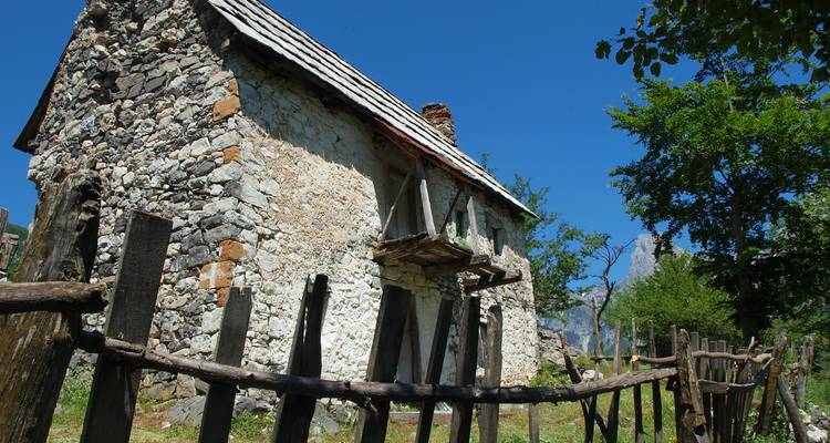 Rural stone house with old fence in a mountain valley.