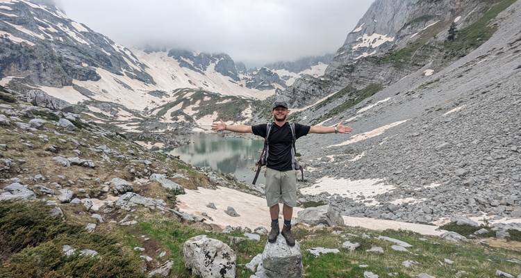 Hiker posing with arms open in foggy mountain scenery.