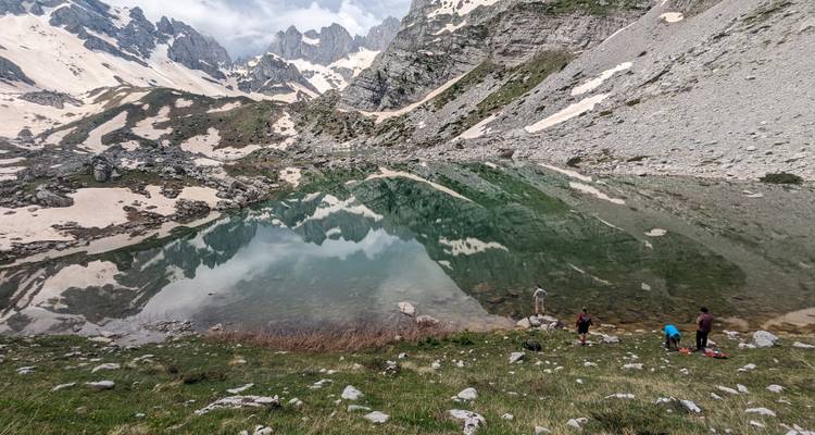 Clear mountain lake with reflections of surrounding snowy peaks.