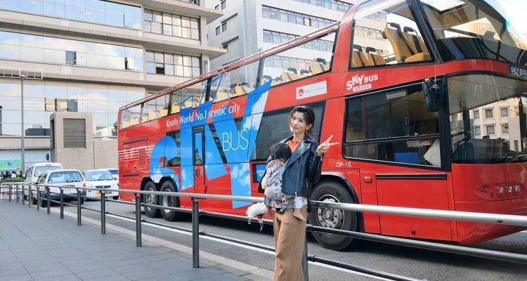 Frau posiert neben einem roten Touristenbus in der Stadt.