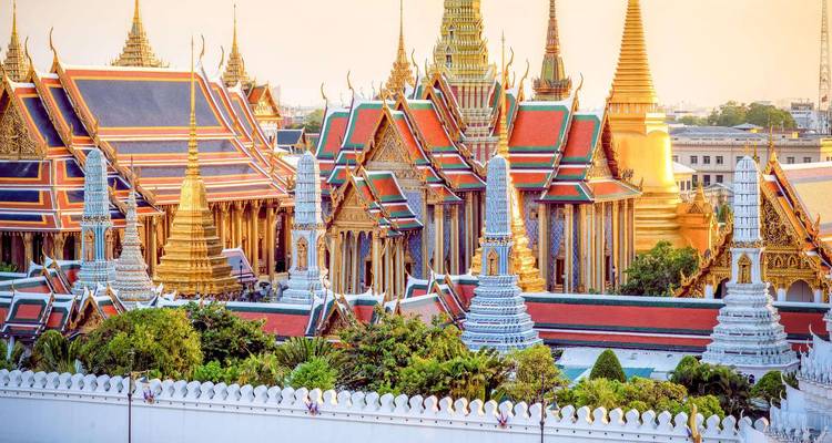 Verhoogd panoramisch zicht op de sierlijke daken en chedi's van het Grand Palace-complex in Bangkok.