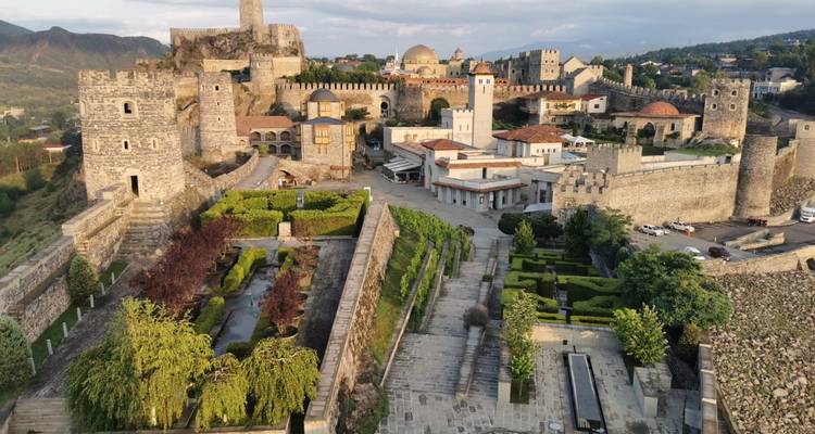 Complejo del Castillo de Rabati restaurado con jardines bien cuidados y torres de piedra bajo la luz del atardecer.