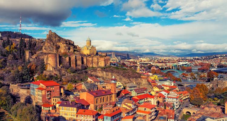 Vista panorámica de Tbilisi con la Fortaleza de Narikala y el río Kura bajo nubes dispersas.