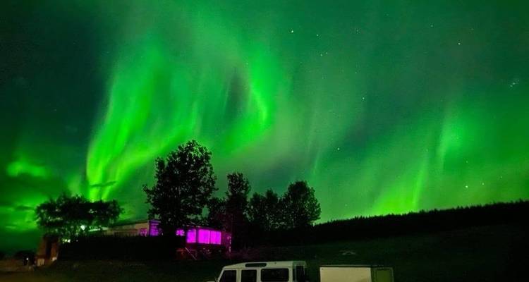 Nordlichter über Gebäuden in der Nacht.