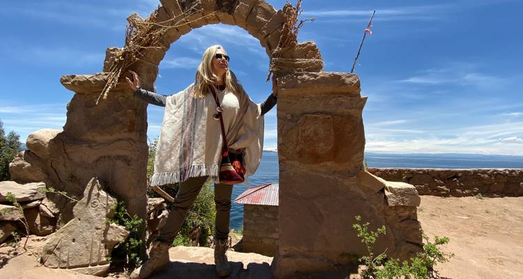 Eine Frau posiert in einem antiken Steinbogen mit Seeblick.