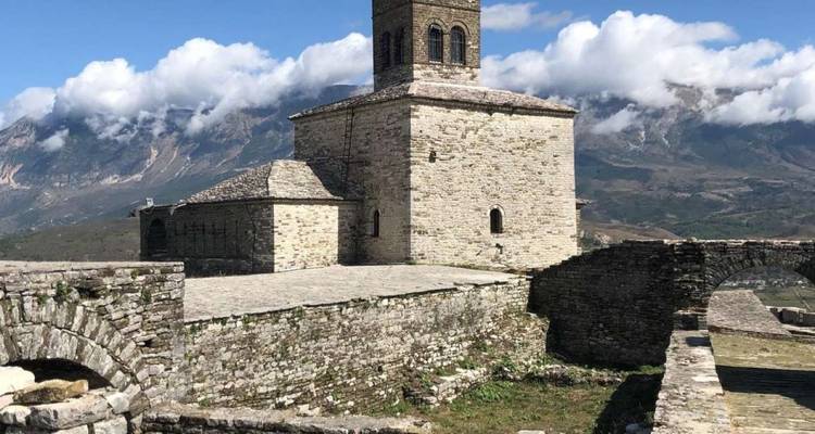 Historisch stenen kasteel met bergachtige achtergrond.