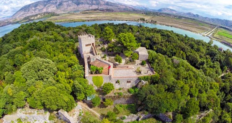 Luchtfoto van een kasteel omringd door bos en water.
