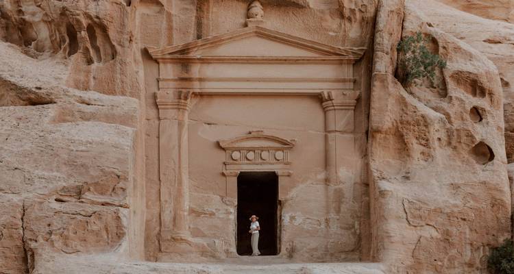 Persoon die voor een gebeeldhouwde stenen gevel staat.