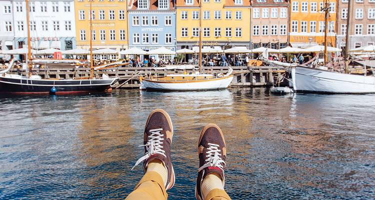 Les chaussures du voyageur pendent au-dessus des eaux réfléchissantes du port coloré de Nyhavn à Copenhague.