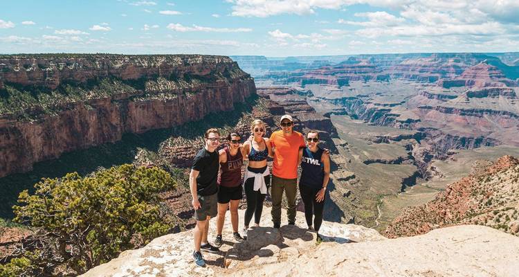 Group of people posing on a cliff at the Grand Canyon.